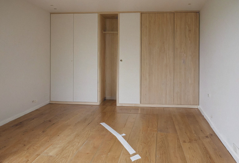 Bedroom floor marked to show clear walking space around a bed and open wardrobe doors