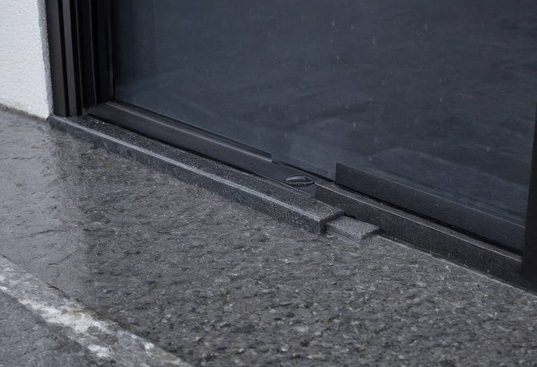 Close view of an entrance threshold joining an exterior sill, recessed mat and porcelain floor