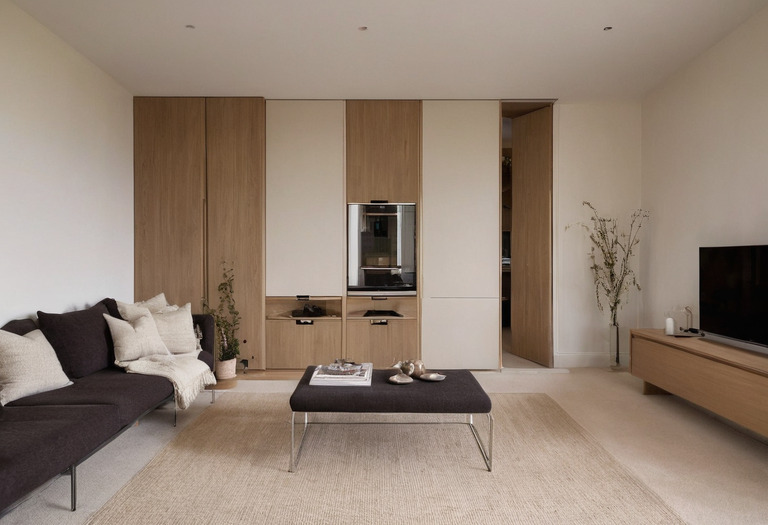 Minimal living room with flush oak storage, a concealed door, and a recessed shadow gap