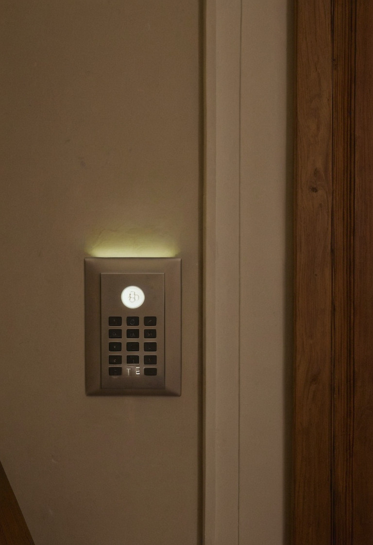 Wall keypad beside a timber doorway with ambient and task lights active beyond